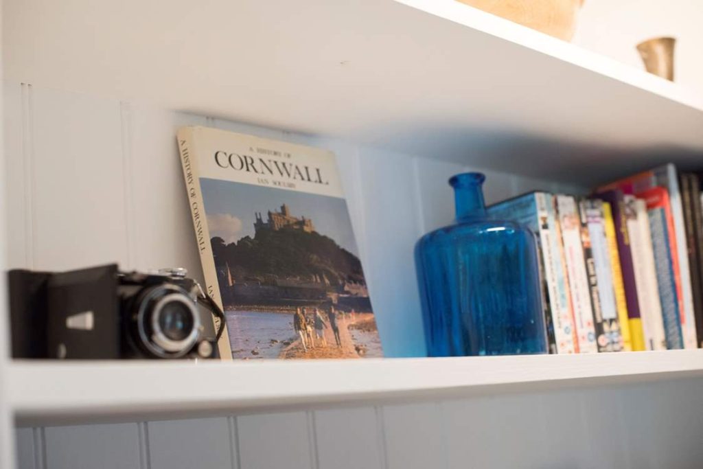 A shelf with a book on Cornwall, blue vase and old fashioned camera