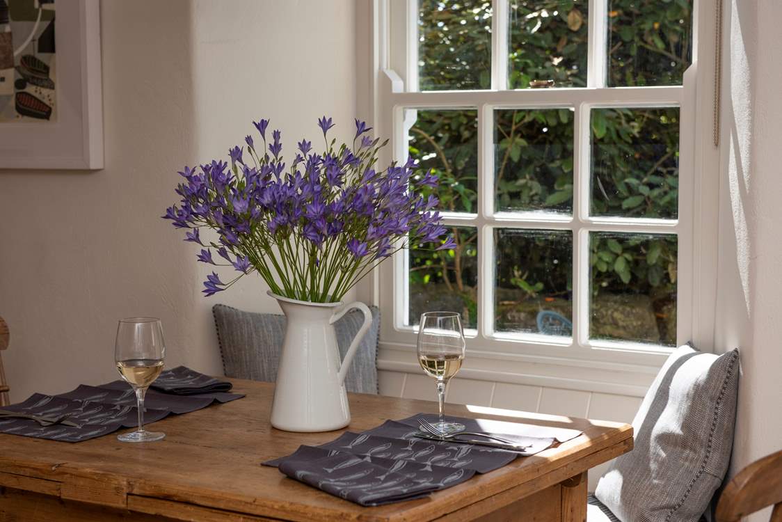 Bunch of flowers in the middle of a wooden dining table with 2 glasses of wine